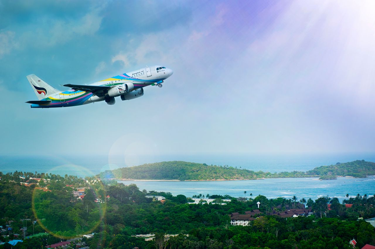 services-01 Airplane soaring over Koh Samui island, Thailand, showcasing a vibrant tropical landscape in daylight.