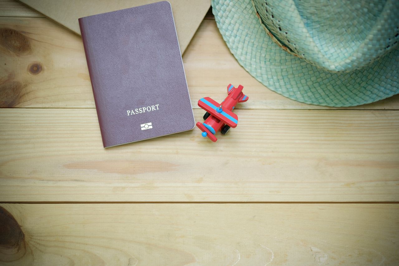 services-04 Flat lay of a passport, straw hat, and toy airplane on a wooden surface.